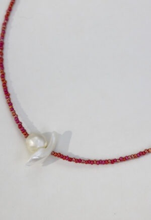 red necklace with pearl center on white backdrop