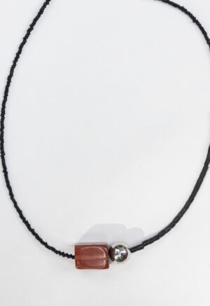 woman in grey top with black and red stone necklace