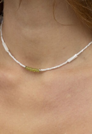 woman in white top and white and green necklace