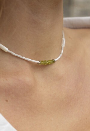 woman in white top and white and green necklace