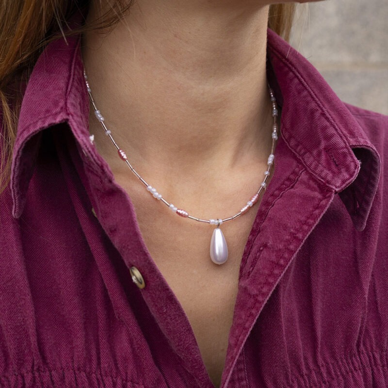 woman in maroon button-up and pink pearl necklace