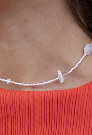 woman in red top with white silver and pearl necklace