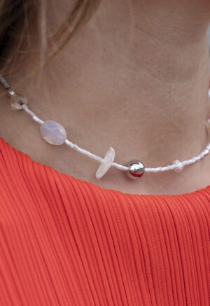 woman in red top with white silver and pearl necklace
