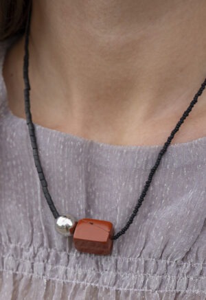 woman in grey top with black and red stone necklace