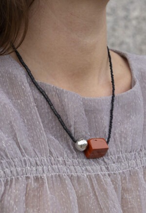 woman in grey top with black and red stone necklace