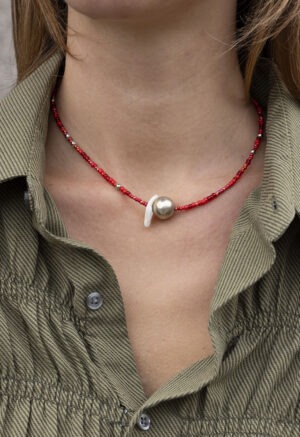 woman in green button-up with red silver and pearl necklace