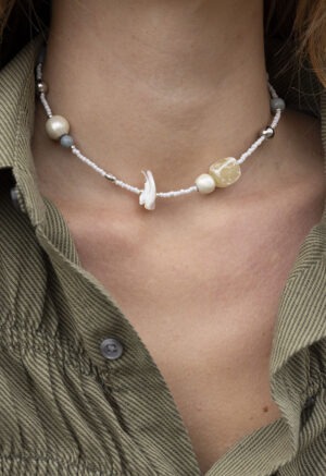 woman in green button-up with white beaded shell and stone necklace