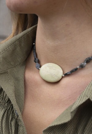 woman in green button-up and dark green stone necklace with large middle center rock