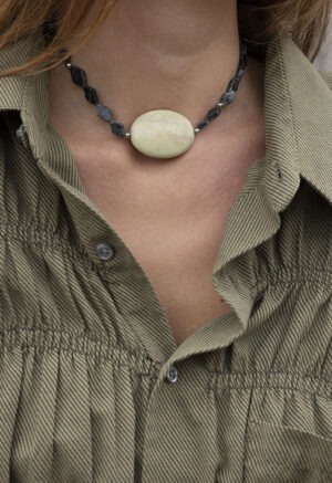 woman in green button-up and dark green stone necklace with large middle center rock