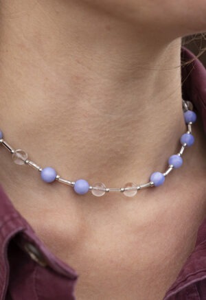 woman in maroon button-up and blue and white beaded necklace
