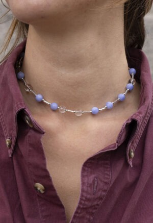 woman in maroon button-up and blue and white beaded necklace