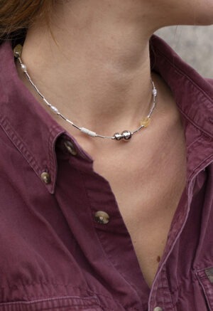 woman in maroon button-up and silver and stone necklace