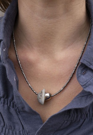 woman in grey button-up with grey and silver shell necklace