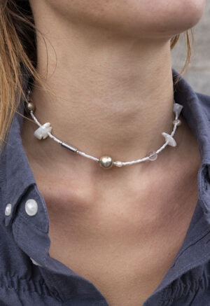 woman in grey shirt in White and silver necklace of various jems