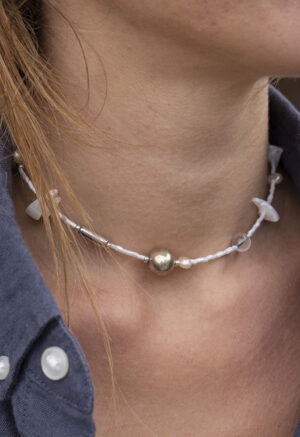 woman in grey shirt in White and silver necklace of various jems