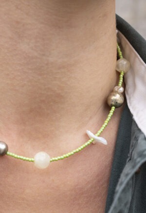 woman in green button-up with light green shell necklace