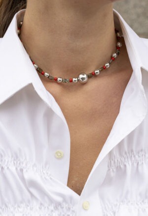 woman in white button-up with red, green and silver necklace