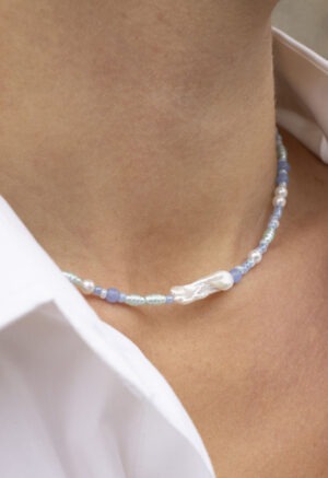 woman in white button-up and blue pearl necklace