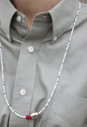 woman in grey button-up with white and grey necklace with silver stone