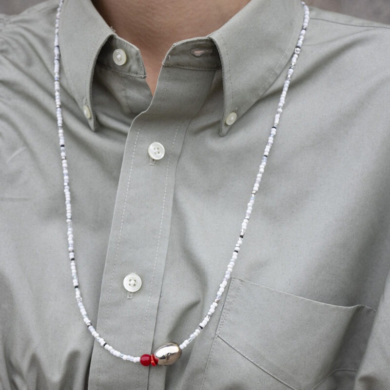 woman in grey button-up with white and grey necklace with silver stone