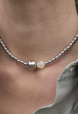 woman wearing grey button-up with silver beaded necklace