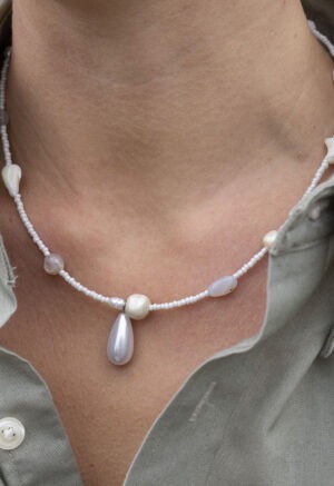 woman in grey button-up and white beaded necklace