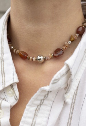 woman in white stripe button-up and tan, brown and rock necklace