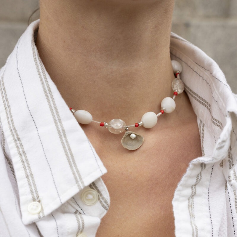 woman in white strip button-up and beaded shell necklace