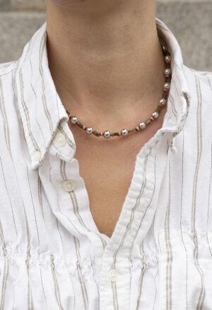Silver, green and red necklace on woman in stripe button-up