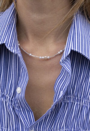 woman in blue and white strip button-up with glass and pearl beaded necklace