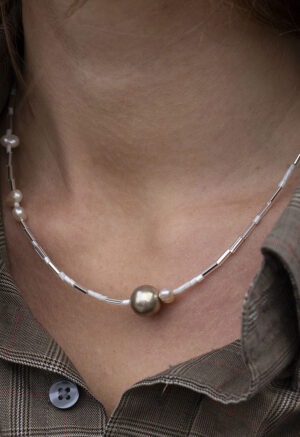 woman in brown plaid shirt and pearl and silver necklace