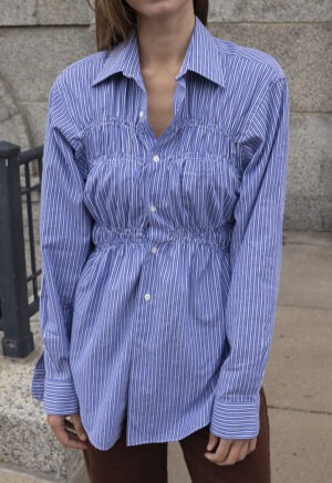 woman in blue and white stripe button-up and brown pants