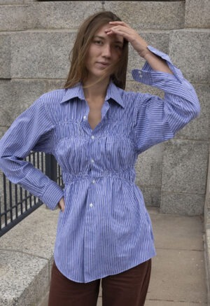 woman in blue and white stripe button-up and brown pants