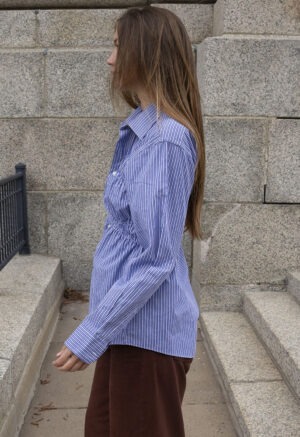 woman in blue and white stripe button-up and brown pants