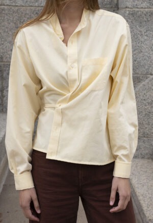 woman in pale yellow button-up wrap top and brown pants