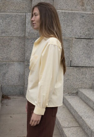 woman in pale yellow button-up wrap top and brown pants