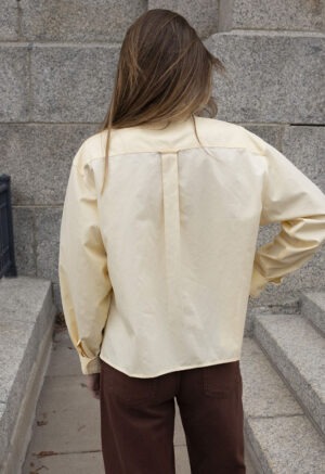 woman in pale yellow button-up wrap top and brown pants