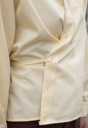 woman in pale yellow button-up wrap top and brown pants