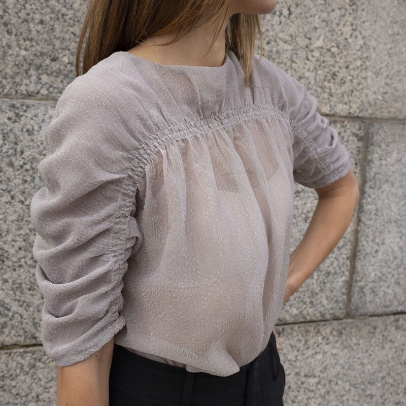 woman in shear ruched top and black trousers