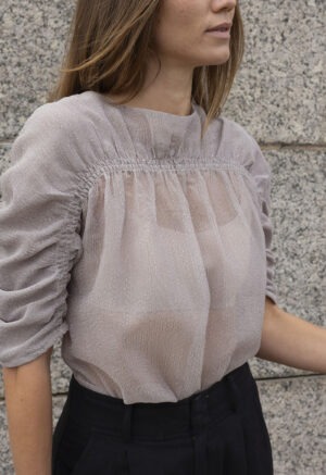woman in shear ruched top and black trousers