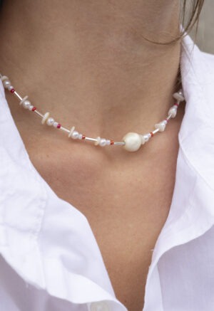 woman in white button-up with pearl, red and silver necklace